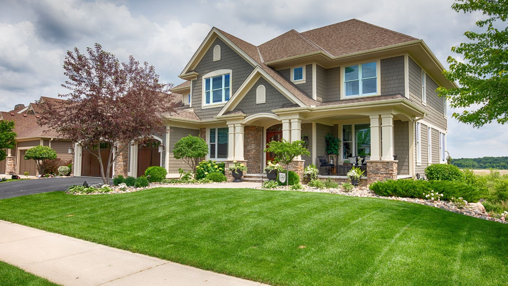 Suburban two-story house with manicured lawn and stone accents